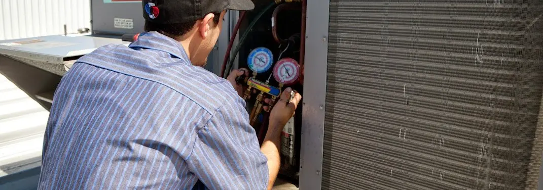HVAC technician servicing a condenser unit in Orange